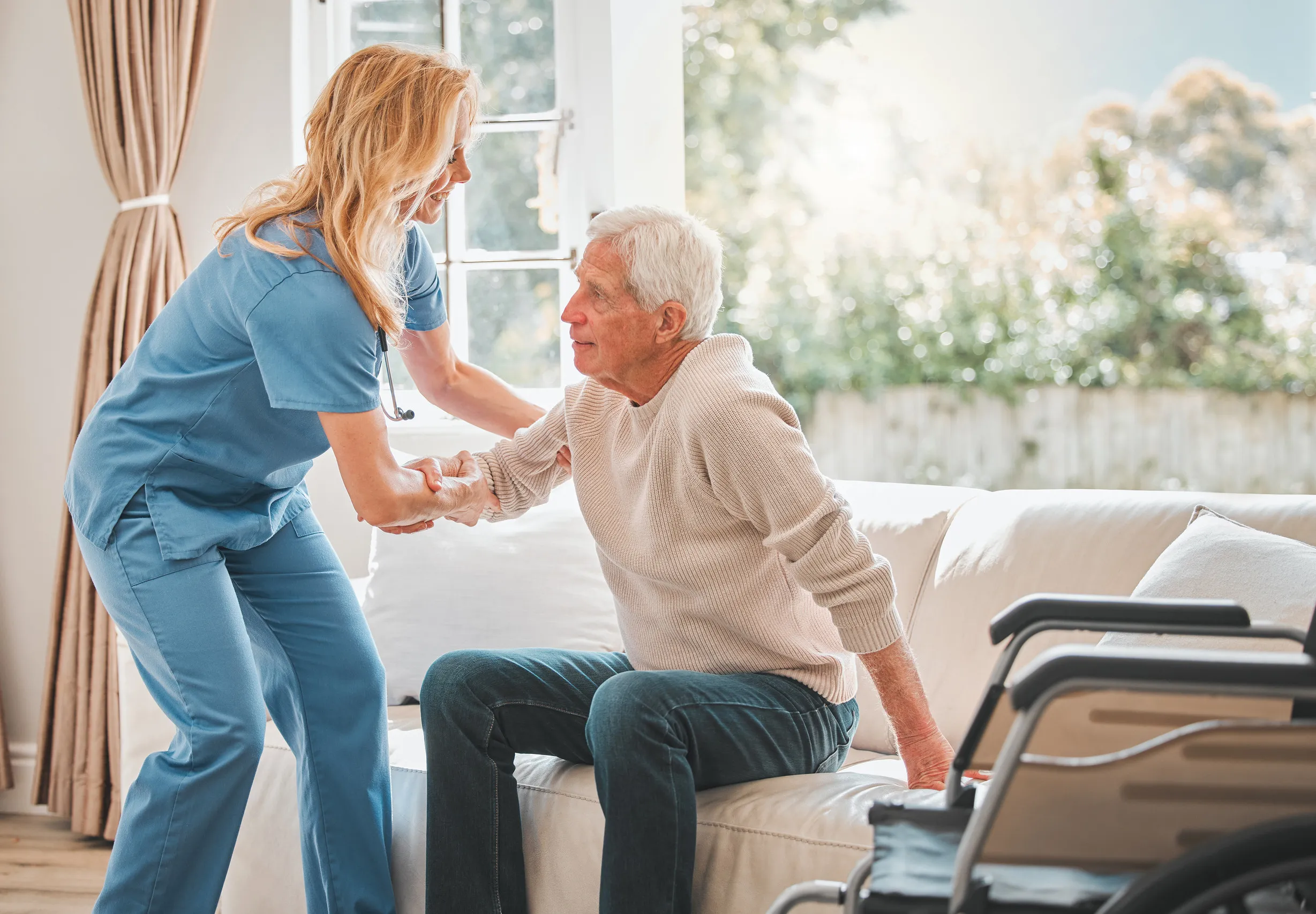 a young nurse helping her elderly male patient stand up